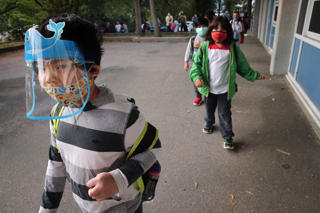 A boy arrives for the first day of school at the Lincoln-Hancock Community School in Quincy, MA on September 17, 2020. Thursday was the first day of in-person learning for half of the students (Cohort B) enrolled in the schools hybrid model. The school also offers a fully remote learning program. (Photo by Craig F. Walker/The Boston Globe via Getty Images)