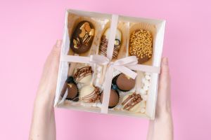 popsicle shaped cake pops and marshmallows in white box on pink background