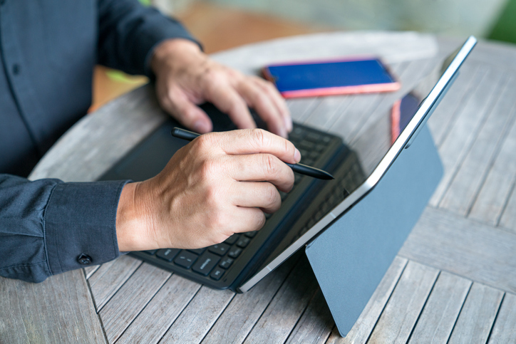 Businessman working on his tablet at home, close up view.
