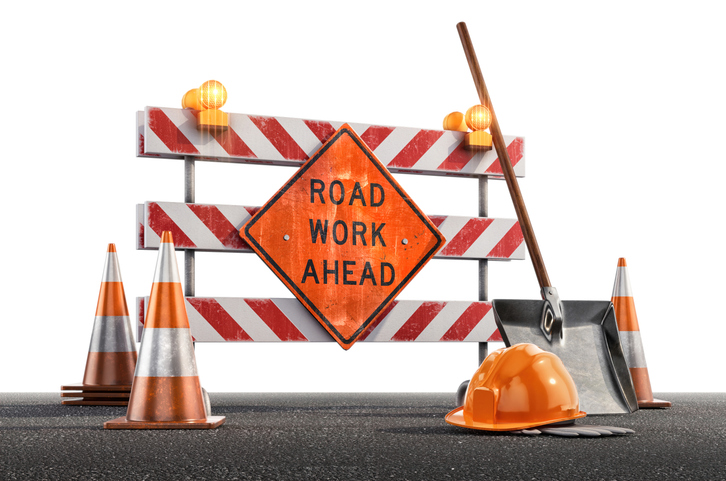 Сonstruction site with a Road Work Ahead sign, traffic cones, hard hat, shovel against a white background.