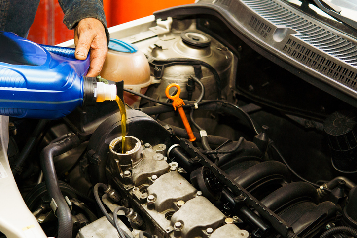 A man is pouring oil into a car engine