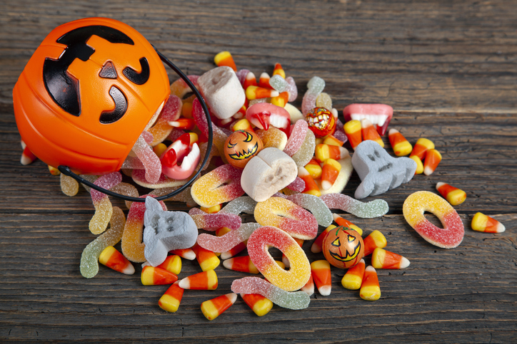 Halloween Jack o Lantern pail with bottom border of spilling candy over brown wood