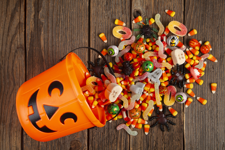 Halloween Jack o Lantern pail with bottom border of spilling candy over brown wood