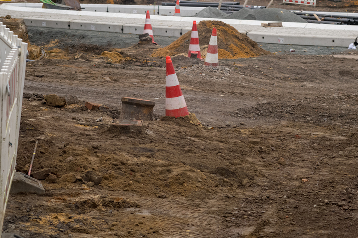 Road construction site with traffic cones and dirt piles