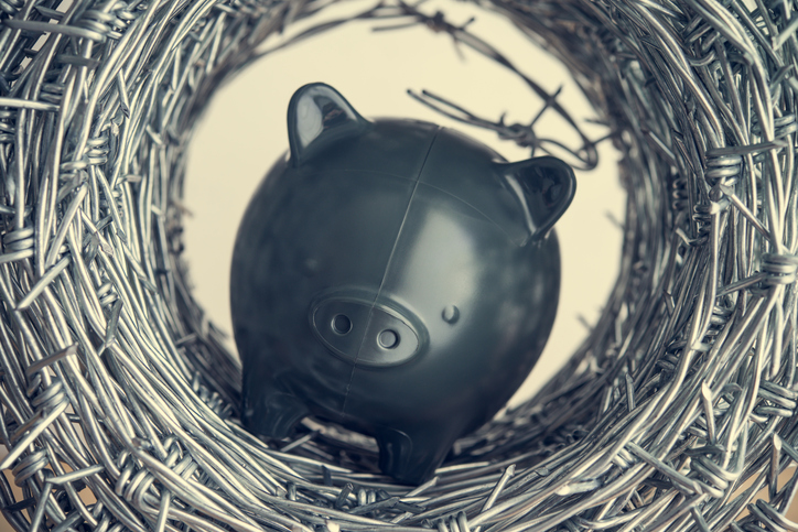 Black piggy bank in barbed wire .