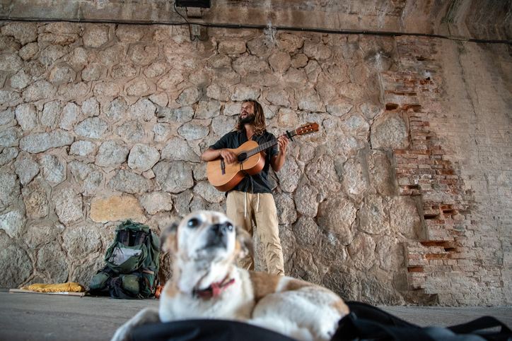 Street musician playing guitar and singing with his dog