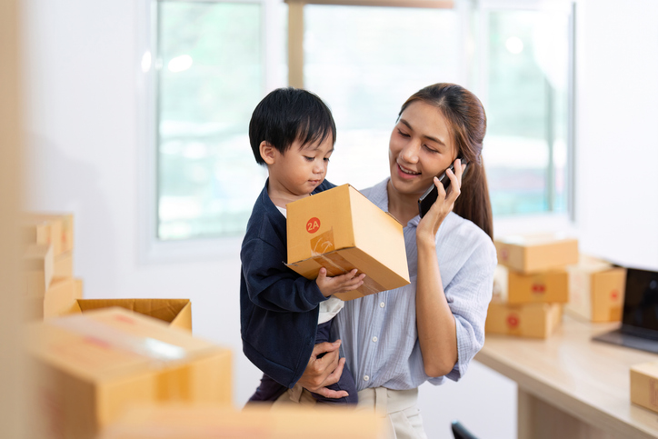 Family Connection. Mother on phone while holding child and managing packages.