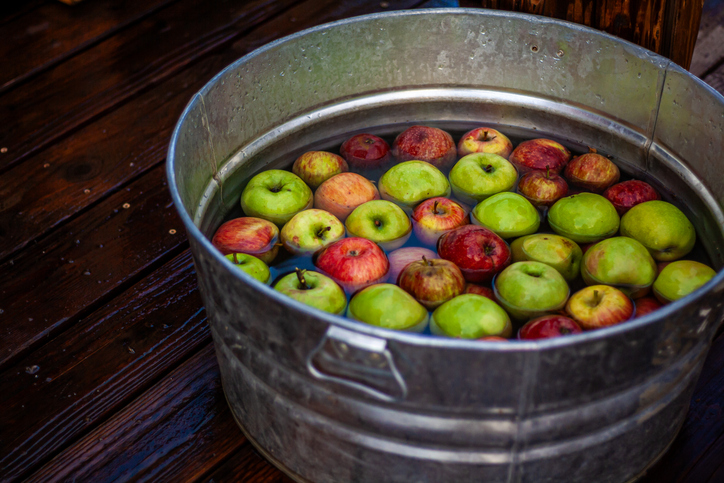 Red and green apples floating in a metal basin