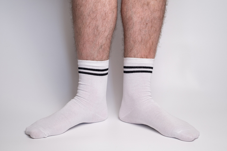 Men's legs in white cotton socks on a white background. Men's feet in new socks. White background with space for text.