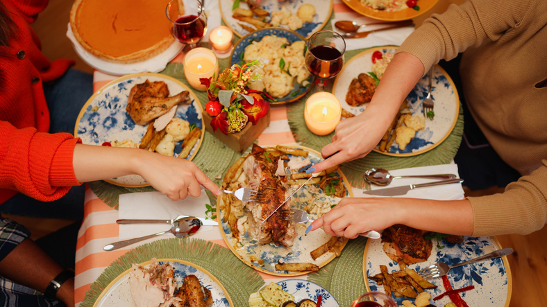 High-angle view of multiracial friends preparing dinner table and meal for dinner party at home